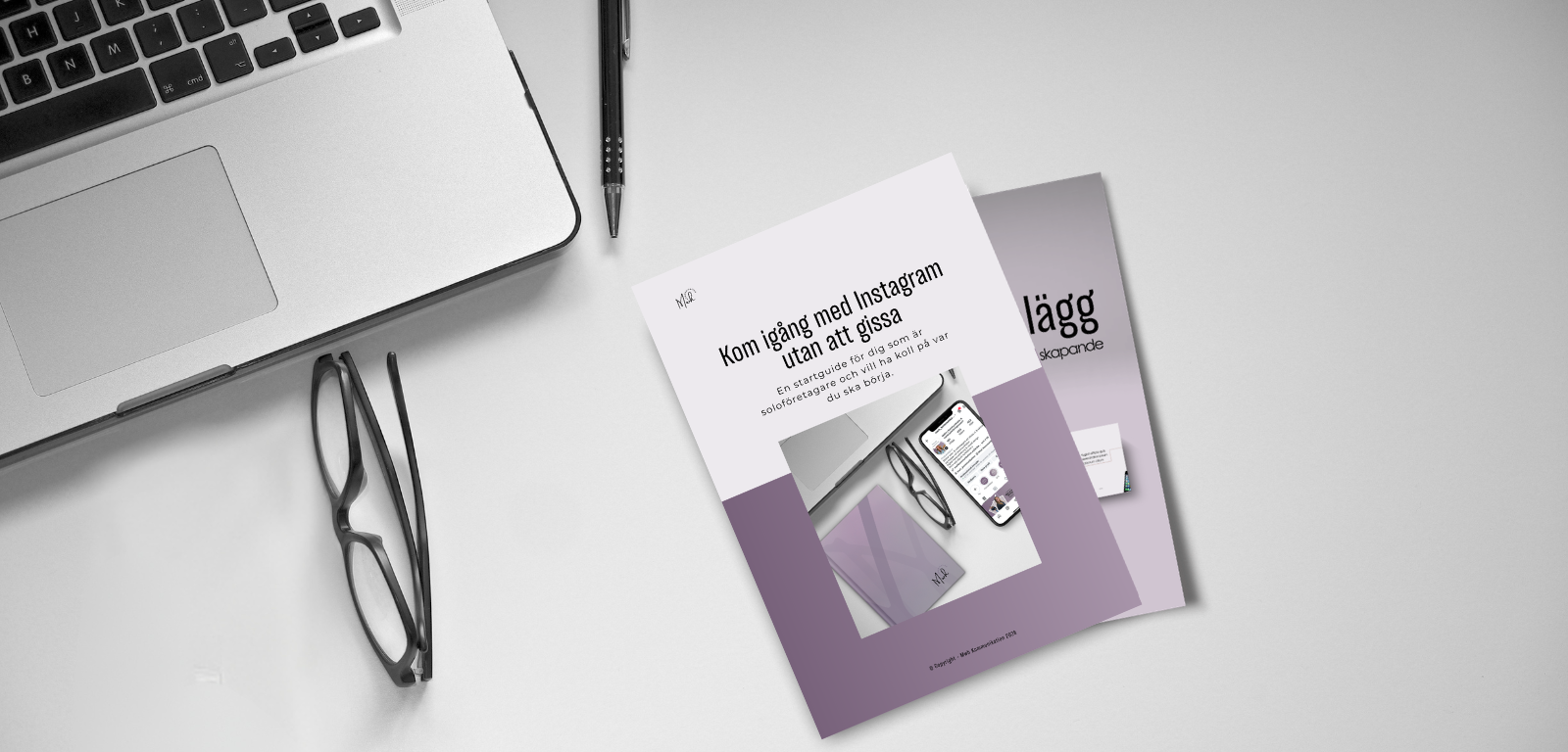 Ett skrivbord med ett hörn av en dators tangentbord, ett par glasögon, en penna och två guider om digital marknadsföring