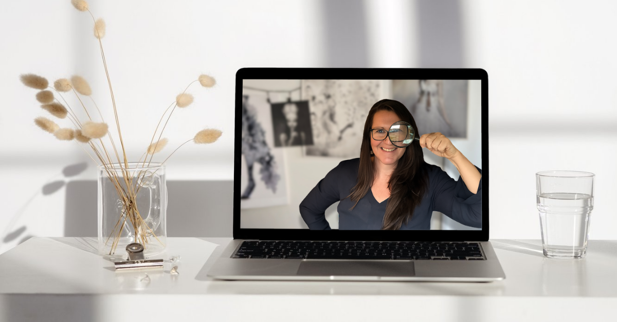 En dator på ett bord där det syns en kvinna som håller ett förstoringsglas framför ena ögat. 