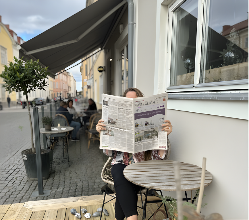 En kvinna sitter å en uteplats och läser 